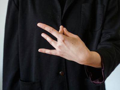 Hands folded in a mudra position with soft blue glow